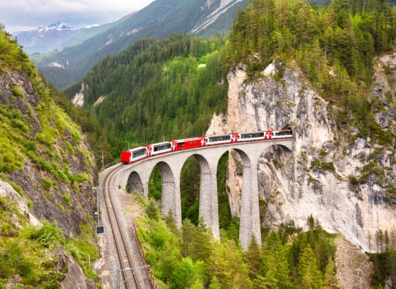 Swiss red train on viaduct in mountain, scenic ride